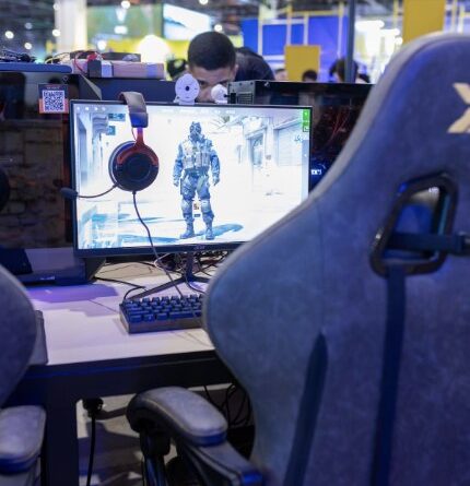 Gaming station at a convention booth during Gamescom 2026, showing a monitor and gaming chair on the show floor