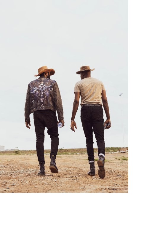 Guns of Eschaton frontier concept art: two figures in cowboy hats walk a dirt road across an empty frontier landscape